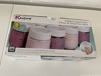 Box top side showing image of 8 glass yogurt jars with white screw-on lids and stay fresh date saver dial. BPA free and dishwasher safe glass jars. Brand Euro Cuisine.