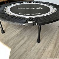 Assembled rebounder on wood floor showing protective padding and set of four steel legs