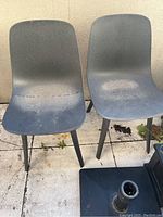Two anthracite chairs with surface dust and marks on seats, showing some discoloration from outdoor storage.