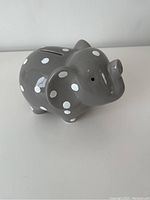 Side view of grey ceramic elephant piggy bank with white polka dots and coin slot on top.