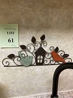Full view of metal wall art showing two birds and a house mounted on a wall