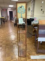 Full view of tall wooden tower with four square shelves and Tree of Life decorative top panel, showing size and structure.