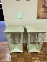 Pair of light green side tables positioned next to a wall on wooden parquet flooring.