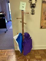 Full view of the small wooden coat rack with bags hanging on its pegs, showing overall height and base.
