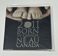 Closed presentation folder front cover showing baby feet photo and title '2011 Born In Canada / Né Au Canada' with one coin displayed.