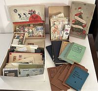 Close-up of vintage and Christmas-themed candy boxes filled with loose stamps, envelopes with stamps, and some albums in the back