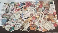 Wide view of a large assortment of vintage liquor labels spread out on a surface showing diverse brands and styles.