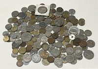 Wide view of a large pile of mixed old coins from many countries showing various sizes, colors, and shapes, mainly circulated.
