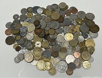 Top down photo showing a large varied pile of over 200 old coins from multiple countries in silver, bronze, and gold tones.