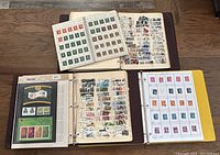 Four vintage stamp albums shown from above with loose stamps on album pages visible, highlighting variety and condition.