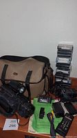 Canon H660 Hi8 camcorder with carrying bag, battery charger, cables, remote, instruction manual, and stack of used Hi8 tapes on wooden surface.