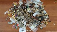 Large pile of tangled chains, bracelets, earrings and charms, many in small zip bags