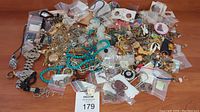 Overview of assorted jewelry pieces on wooden surface including necklaces, bracelets, earrings, charms, and beads