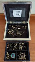 Close up of black velvet lined jewelry box top compartment with necklaces, chains, and small pendants