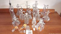Overview of multiple vintage crystal and glass cruets and perfume bottles arranged in a group showing variety of shapes and stoppers.