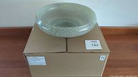 Top view of the glass bowl on top of a large cardboard box with labels.