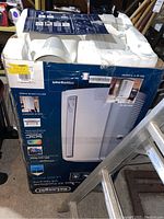 Original box and foam packaging of DeLonghi portable air conditioner with vent hose parts included.