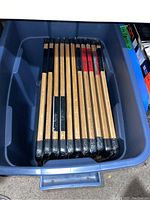 Blue plastic bin containing 10 bamboo cutting boards stacked vertically, each with black non-slip corner guards and wrapped in plastic.