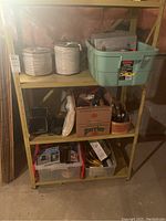 Shelving unit with spools of cable, plastic bin with toolbox and cables, black speakers, and plastic boxes