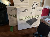 Two shrink-wrapped Seagate Expansion desktop drive boxes on wooden surface showing quantity and packaging