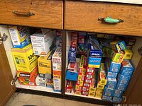 Full view of the cabinet shelf containing multiple boxes of household storage bags and foil, showing brand names and counts.