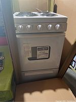 Front view of electric range showing control knobs, oven door closed