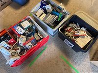 Three plastic totes on floor filled with assorted cables, cords, power bars, and timers.