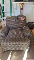 Front angled view of armchair showing shape, seat, and armrests with patterned upholstery and patches on backrest and right armrest.