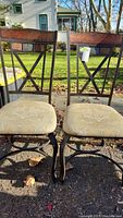 Front view of two metal framed dining chairs with wooden backs and fabric seats showing design and condition.