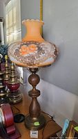 Full view of lamp showing wood base, metal fixture and hand-painted glass shade with floral design.