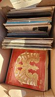 Photo showing the box of LP records stacked vertically, with visible album cover featuring ornate classical artwork and titles visibly in the classical and Christmas genres.