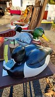 Group photo showing two Van Sciver duck decoys and one smaller decorative duck on wood base displayed outdoors.