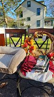 Wreath, pet bed, and folded table linens displayed on two chairs outside