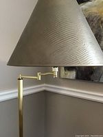 Close-up photo of the top part of the lamp showing the articulated arm and textured conical lampshade
