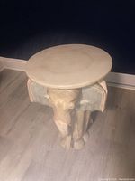 Full top view of round marble table top and carved elephant base under soft lighting.
