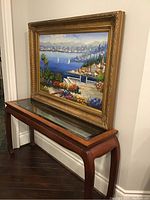Full view of painting and frame displayed on wood console