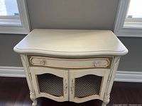 Front view of Thomasville nightstand showing curved legs, drawer with two crystal knobs and two mesh front doors with decorative metal handles.