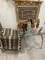 View of the collection displayed on and above a glass table showing sculptures, dolls, and textiles.