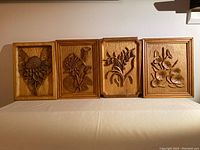 All four wood relief plaques displayed side by side