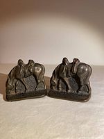 Front view of both cast iron horse bookends showing grazing horses with saddles.