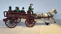 Side view of antique cast iron fire wagon with horse and figures attached