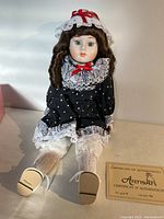 Front view of 16-inch porcelain collector doll "Dorothy" seated, showing detailed facial features, clothing, and Certificate of Authenticity placed beside.