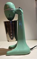 Side view of vintage Hamilton Beach Drink Master drink mixer in mint green with stainless steel cup attached.