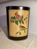 Full front view of waste basket showcasing black metal body with central cardinal bird print panel.