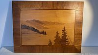 Full front view of handcrafted wooden marquetry panel depicting a serene mountain landscape and pine trees.
