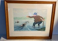 Framed watercolour print depicting a man and dogs in a river scene, signed by Boris O'Klein.