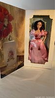 Doll inside box showing gown and accessories with Valentine-themed backdrop