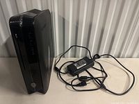 Front and left side view of the Alienware X51 R3 small form factor tower with included AC adapter and power cord.