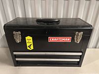 Closed view of black Craftsman metal tool chest with two front latches and a handle on top.