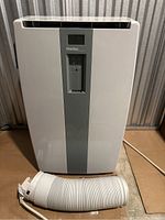 Front view of white Danby Designer portable air conditioner with exhaust hose coiled at base.